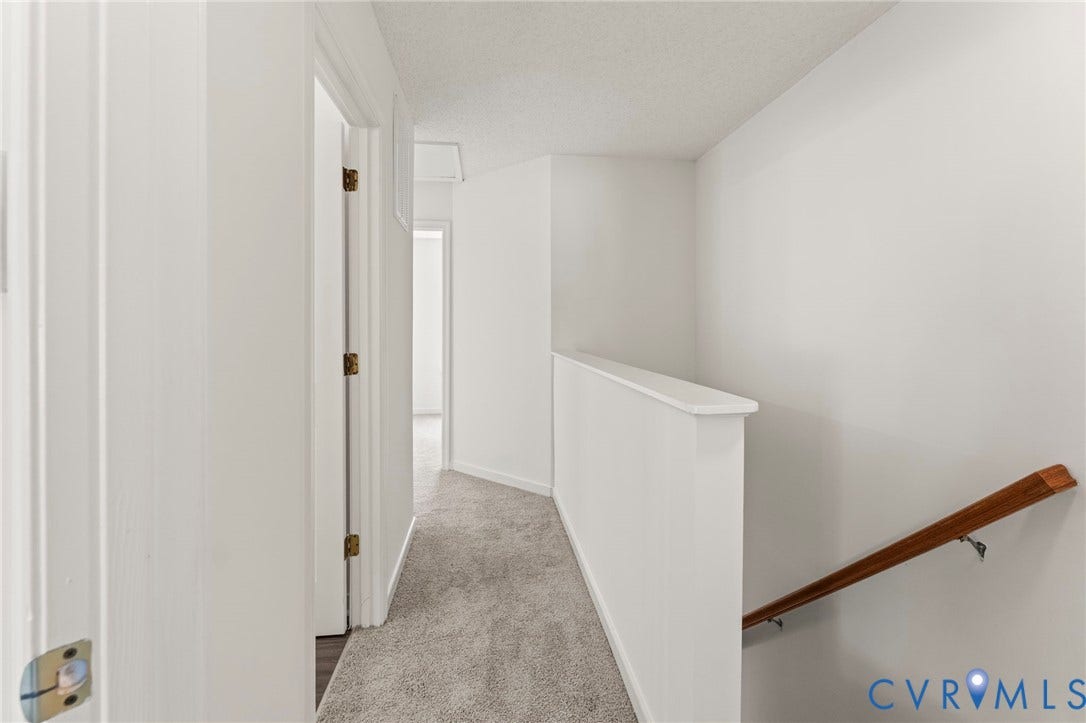 10111 Robin Lee Lane, Henrico, VA 23060 Bright hallway featuring clean white walls, wood-finish railing, neutral carpet flooring, and multiple door openings with brass hardware