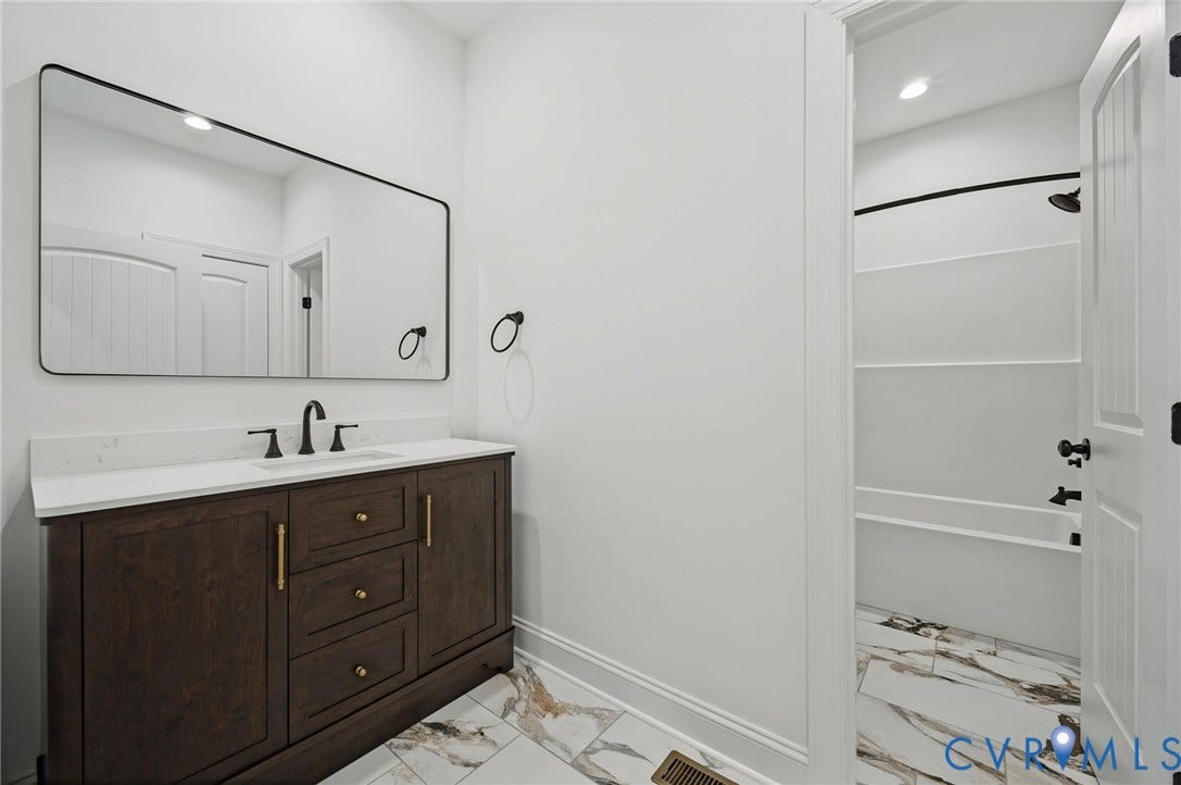 6995 Jefferson Highway, Louisa, VA 23117 Dark wood vanity with a white countertop and black-framed rectangular mirror
