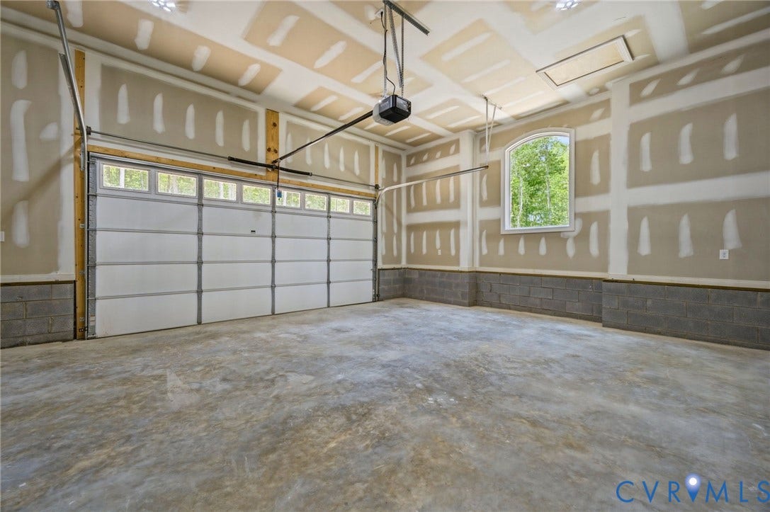 6995 Jefferson Highway, Louisa, VA 23117 Spacious garage featuring a concrete floor, an arched window, a sectional garage door with upper lites, an automatic garage door opener, and unfinished drywall walls