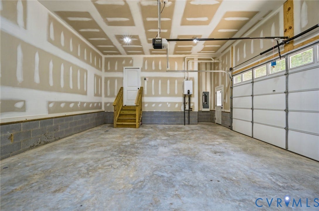 6995 Jefferson Highway, Louisa, VA 23117 Spacious two-car garage featuring a concrete floor, insulated garage door with transom windows, and an interior access door with wooden stairs