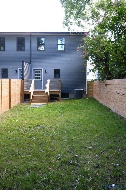 1514 Custer Street, Richmond, VA 23222 Spacious backyard featuring a substantial lawn area, a privacy fence, and an elevated wood deck with stairs leading to a back entrance
