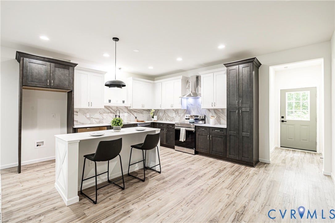 1514 Custer Street, Richmond, VA 23222 Contemporary kitchen featuring two-tone cabinetry with white upper and dark lower units, a central island with countertop seating, and light wood-finish flooring