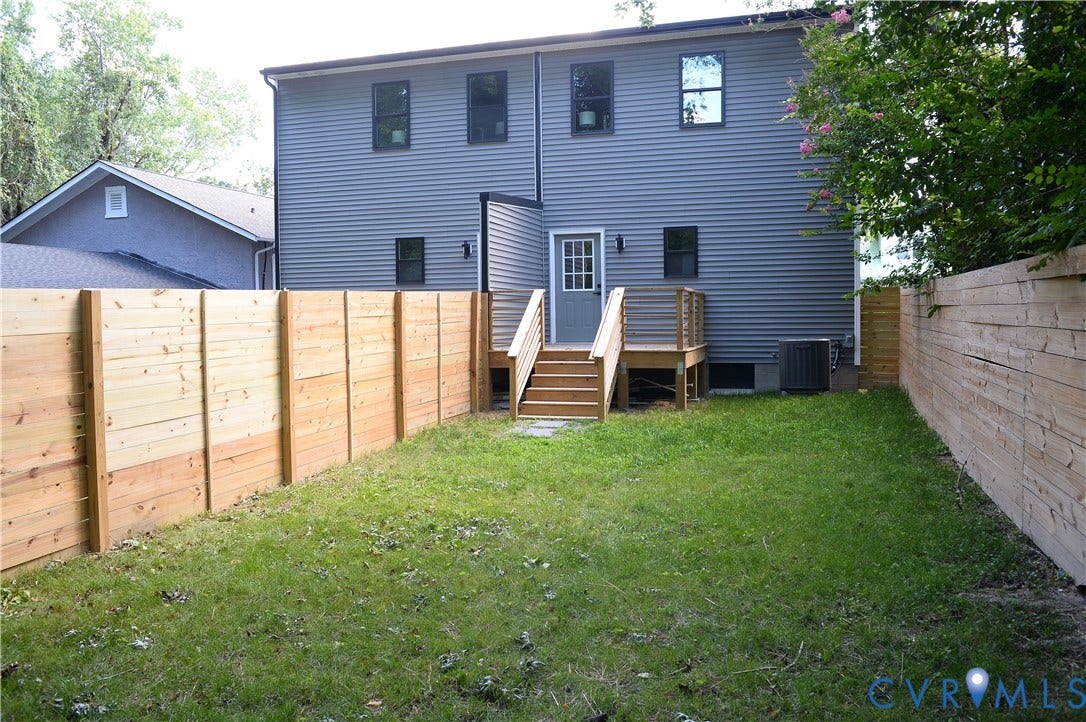 1514 Custer Street, Richmond, VA 23222 Spacious backyard featuring a wooden privacy fence, a verdant lawn, and a wooden deck with stairs leading to the back entrance