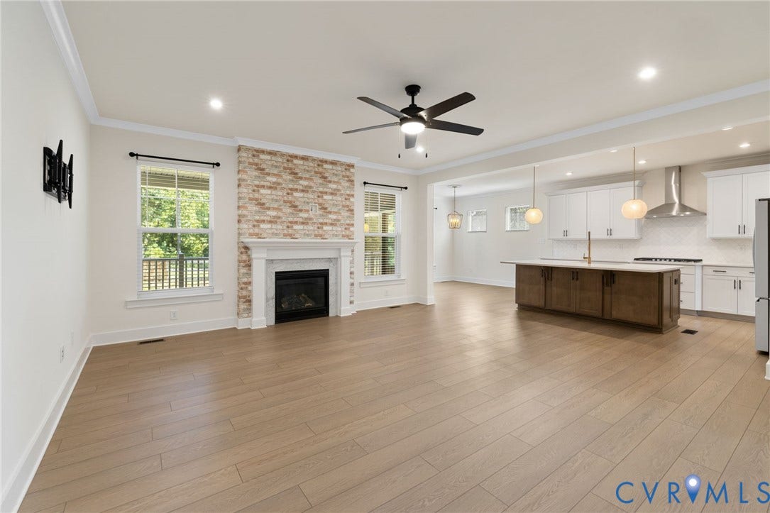 Open concept living space featuring wood-finish flooring, fireplace with a white mantel, and recessed lighting