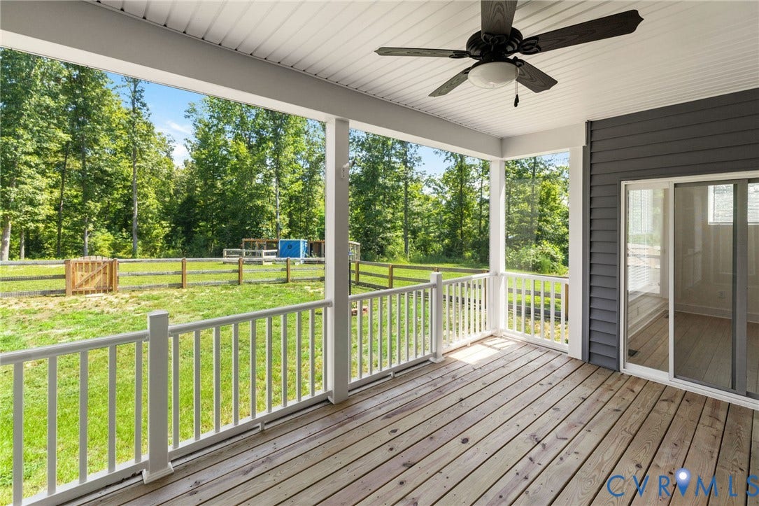 Covered porch featuring a ceiling fan, white railing, wood-finish decking, and sliding glass door