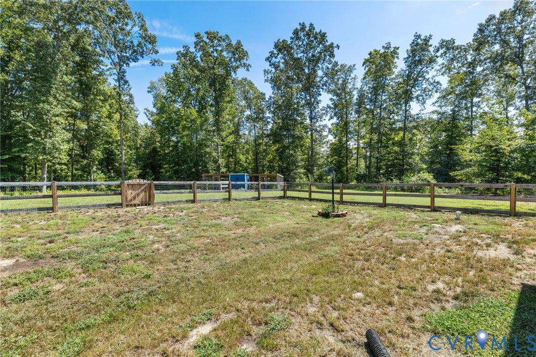 Expansive outdoor space featuring a wood fence, gate, and mature trees