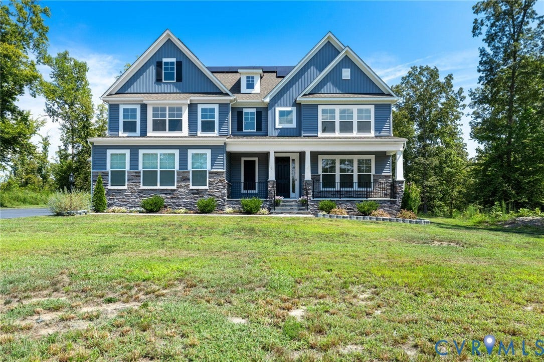 Two-story residence featuring blue siding, stone facade accents, multiple gables, a covered front porch, and a dormer window