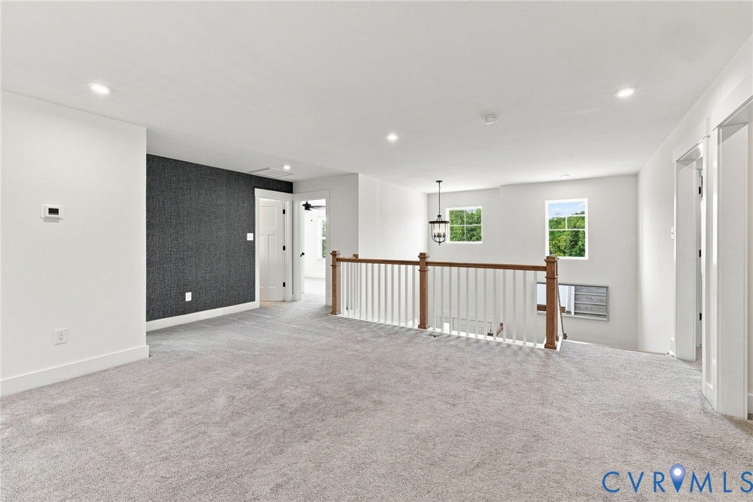 Carpeted upper-level landing featuring a wood and white spindle railing, recessed lighting, and two windows