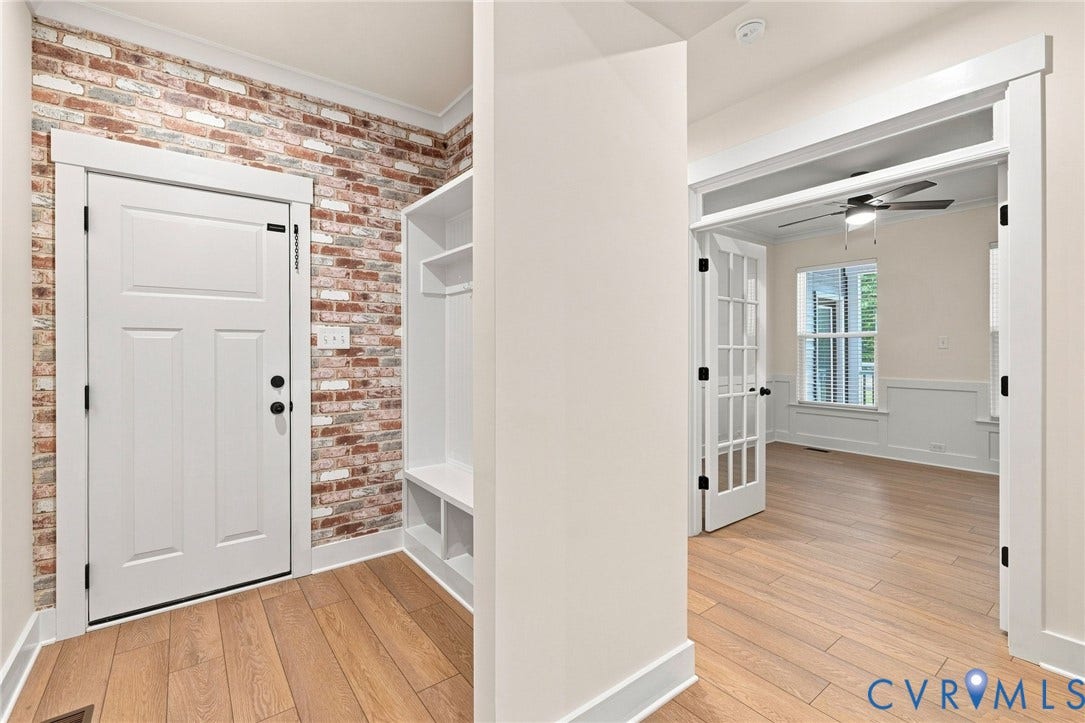 Wood-finish flooring, built-in storage bench, and French doors leading to a room with wainscoting