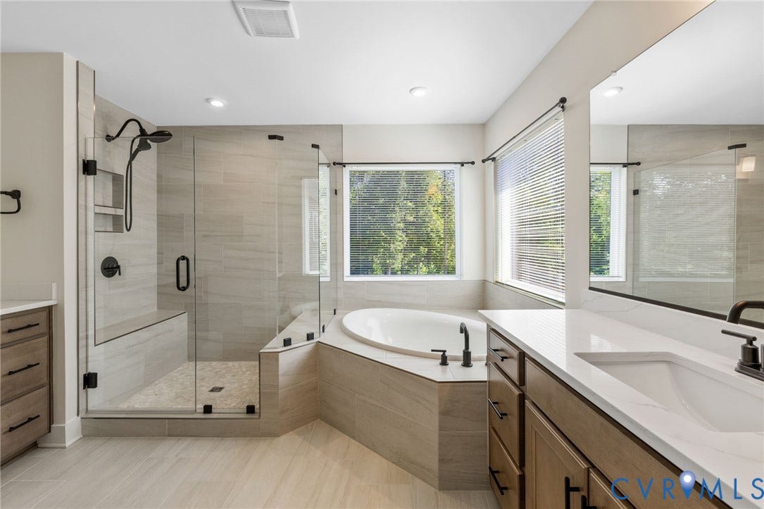 2nd floor primary ensuite. Spacious bathroom featuring a built-in soaking tub, walk-in shower with bench seating, dual vanity with undermount sinks, and large windows