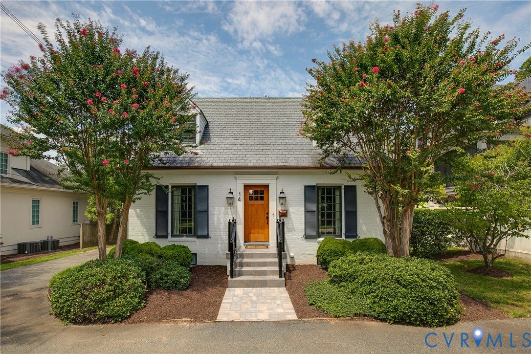 14 Libbie Avenue, Libbie/Grove, Richmond, VA 23226 White brick facade with dark shutters, a light wood entry door, and a shingled roof featuring a dormer window
