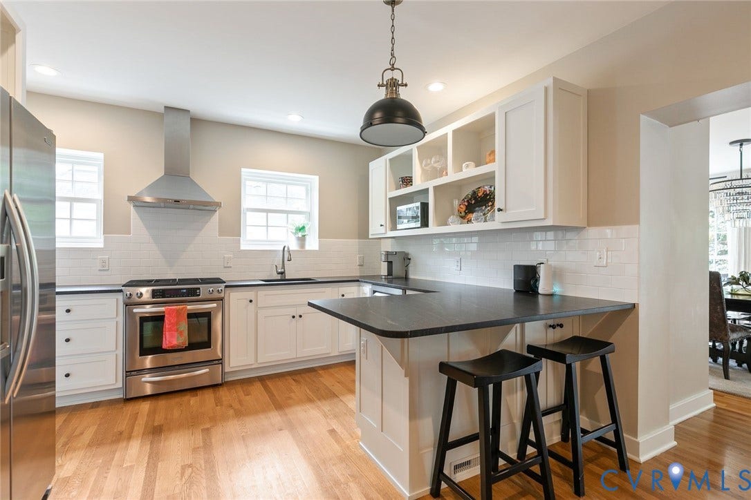 14 Libbie Avenue, Libbie/Grove, Richmond, VA 23226 Kitchen featuring white shaker cabinetry, stainless steel range with overhead hood, black countertops, white subway tile backsplash, and wood-finish flooring