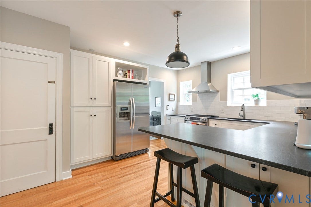 14 Libbie Avenue, Libbie/Grove, Richmond, VA 23226 Modern kitchen featuring a stainless steel refrigerator, white cabinetry, a large kitchen island with seating, a stainless steel range hood, and wood-finish flooring
