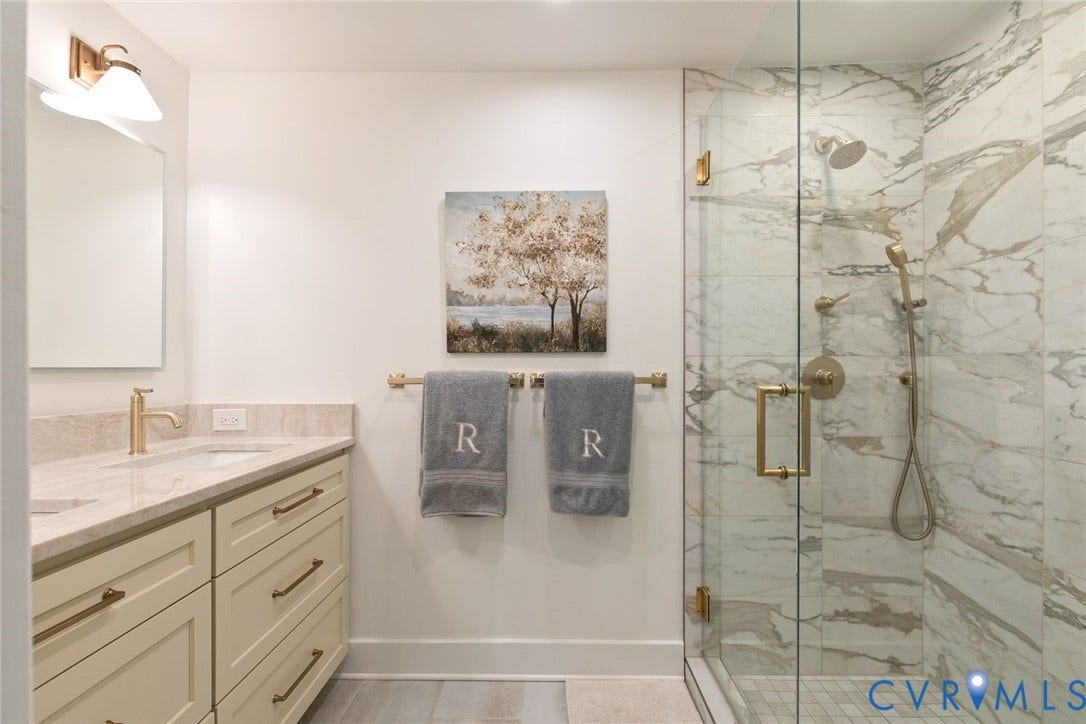 14 Libbie Avenue, Libbie/Grove, Richmond, VA 23226 Bathroom featuring a glass-enclosed shower with stone-finish tile surround and brass-tone fixtures, a double vanity with a light-toned countertop, and recessed lighting