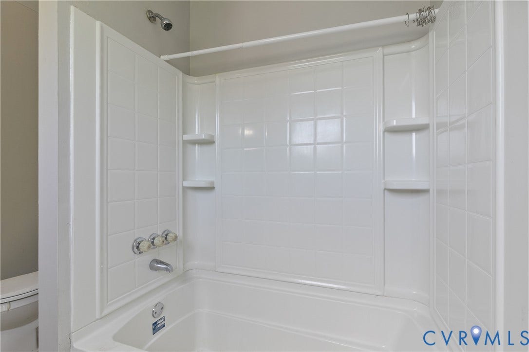 2801 4th Avenue, Richmond, VA 23222 Bathtub and shower combination featuring white tiled surround, integrated shelving, and polished chrome fixtures