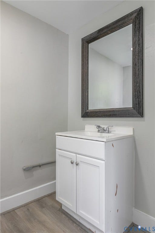 2801 4th Avenue, Richmond, VA 23222 White vanity with integrated sink and chrome faucet, set against a light gray wall with wood-finish flooring and a distressed wood-framed mirror