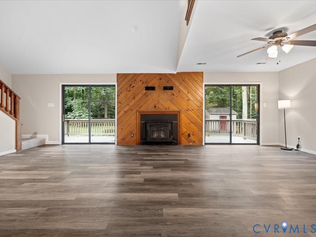 508 Smoketree Place, Chesterfield, VA 23236 Spacious living area featuring luxury vinyl flooring, a wood-burning stove with a stone hearth, and a wood-paneled accent wall