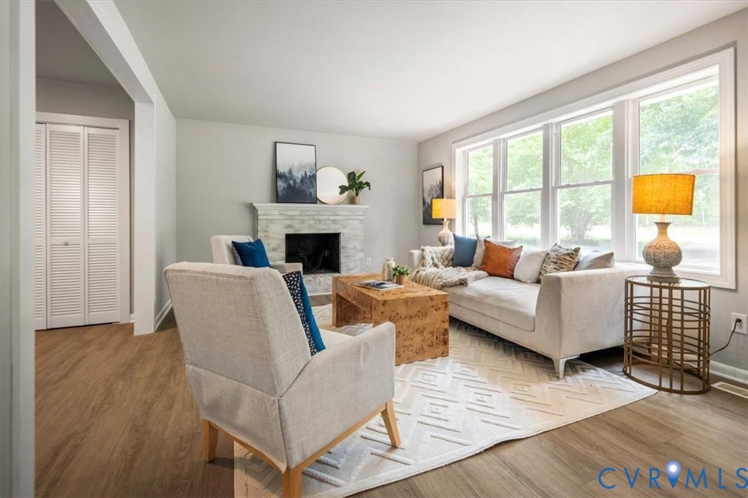 4400 Treely Road, Chesterfield, VA 23831 Living room featuring wood-finish flooring, a white mantelpiece, a fireplace with dark stone surround, a wide window with multiple panes, and white bi-fold louvered doors