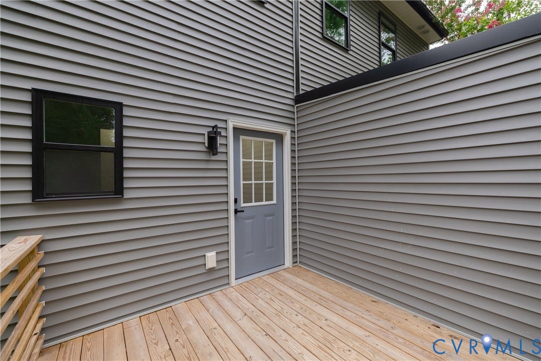 1516 Custer Street, Richmond, VA 23222 Exterior deck space featuring wood-finish flooring, gray siding, a door with window panes, a black exterior light fixture, and black-framed windows