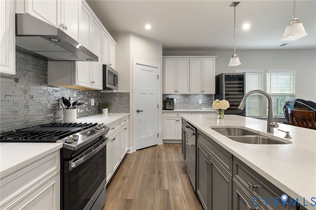 6249 Deer Summit Court, Charleston Club, Moseley, VA 23120 Gourmet kitchen with white cabinetry, stainless steel appliances, a large center island, quartz countertops, and LVP flooring