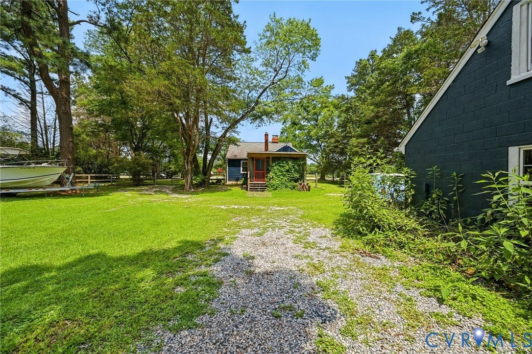 3633 Darbytown Court, Henrico, VA 23231 Gravel driveway opening to a spacious lawn, bordered by mature trees and a fenced area