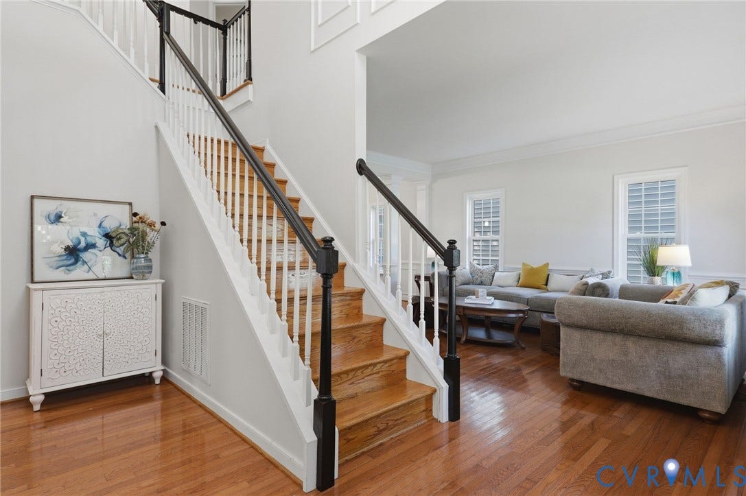 7618 Hampton Green Drive, Chesterfield, VA 23832 Hardwood flooring throughout, a two-story foyer, a staircase with white risers and dark wood handrails, and a living area with multiple windows