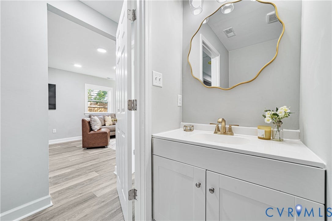 4502 Bunn Avenue, Fulton, Richmond, VA 23231 Bathroom vanity featuring a white countertop with integrated sink, brass-finish faucet, and a decorative gold-framed mirror