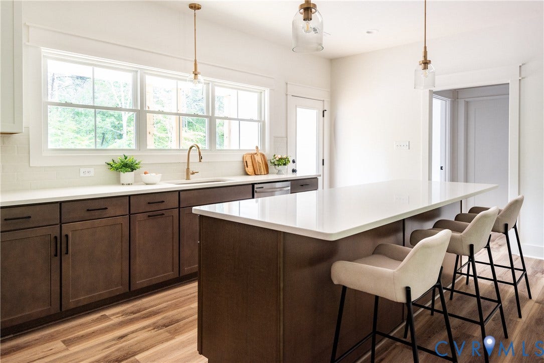 Kitchen featuring a large central island with seating, a white countertop, and LVP flooring