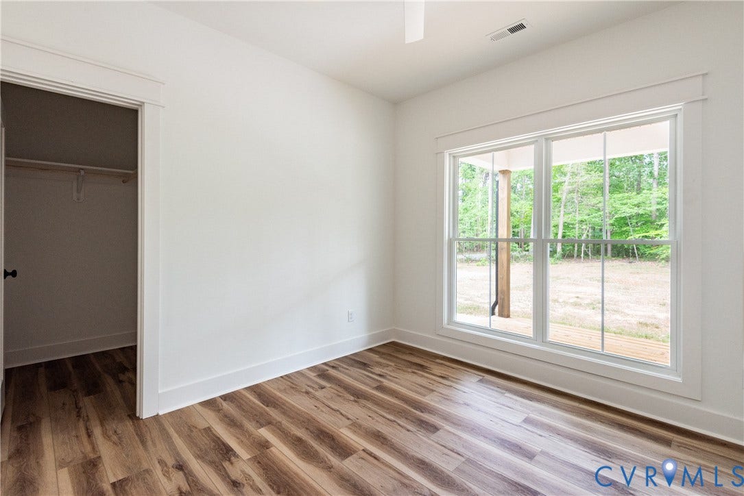 Bedroom featuring LVP flooring, a large window with white trim, and a closet with a black doorknob