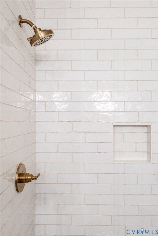 Shower enclosure featuring white subway tile, a recessed niche, and bronze-finish fixtures including a shower head and single-handle valve
