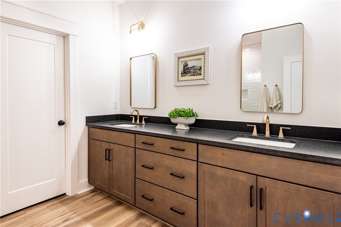 Dual vanity featuring light wood-finish cabinetry, dark countertops, and undermount sinks