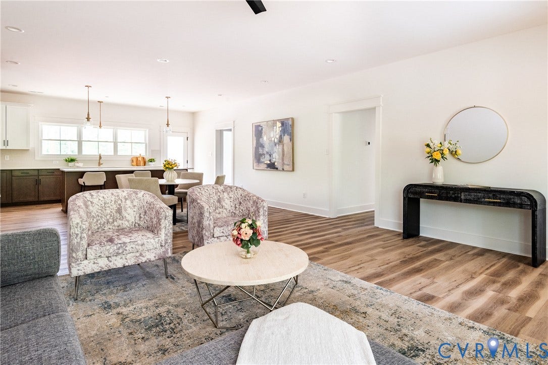 Open-concept living space featuring LVP flooring, recessed lighting, white walls, and a kitchen with white upper and dark lower cabinetry and pendant lighting