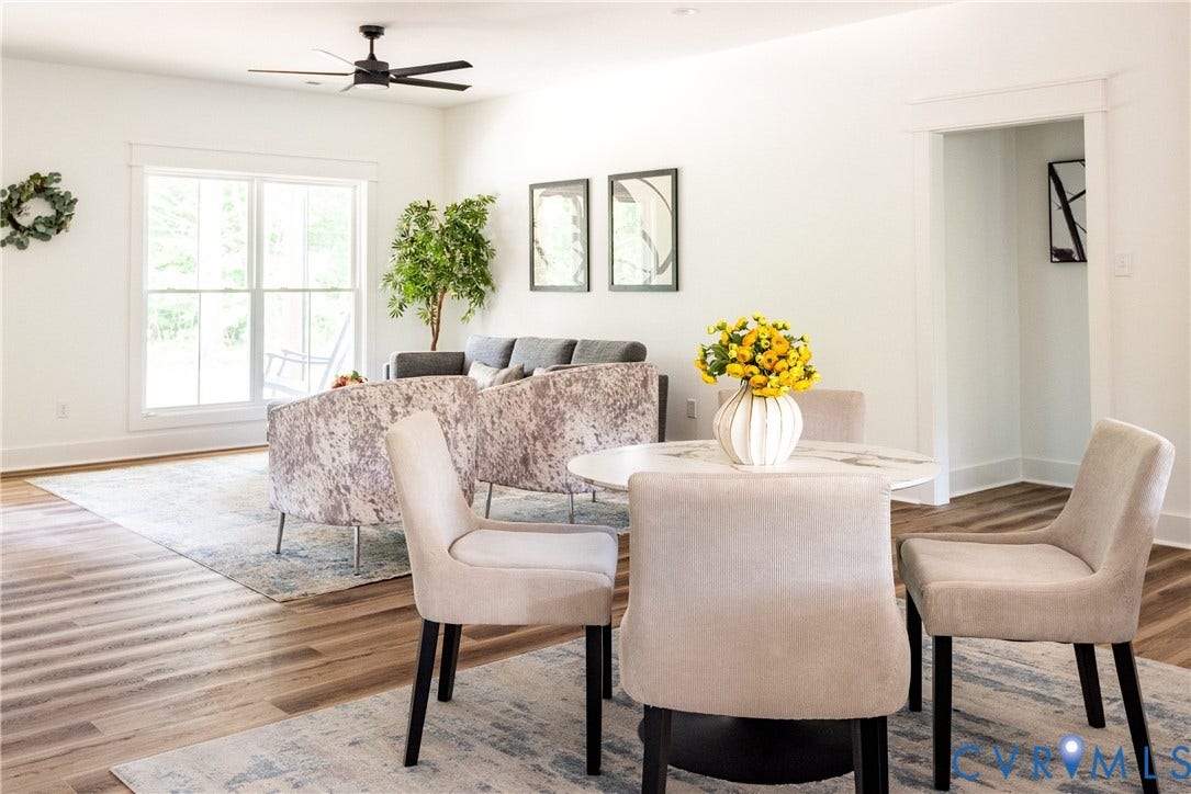 Spacious open-concept room featuring wide plank LVP flooring, a contemporary ceiling fan, large windows with white trim, and a bright white color palette