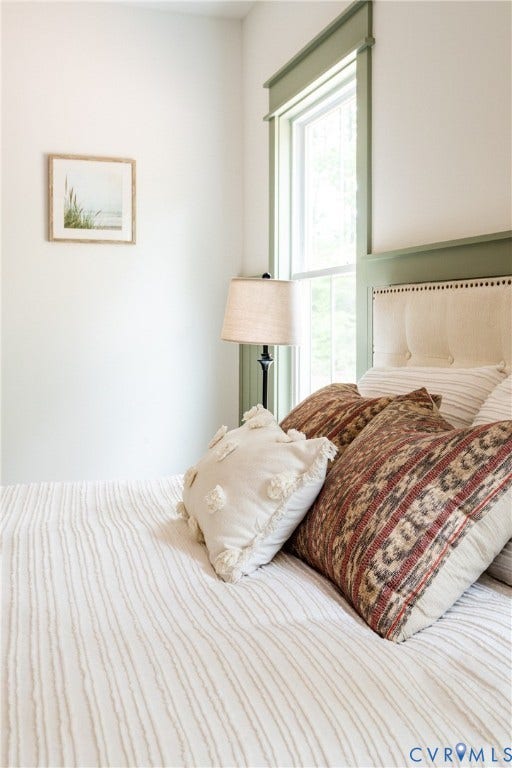 Bedroom featuring a tall window with decorative green trim and a coordinating green wall accent