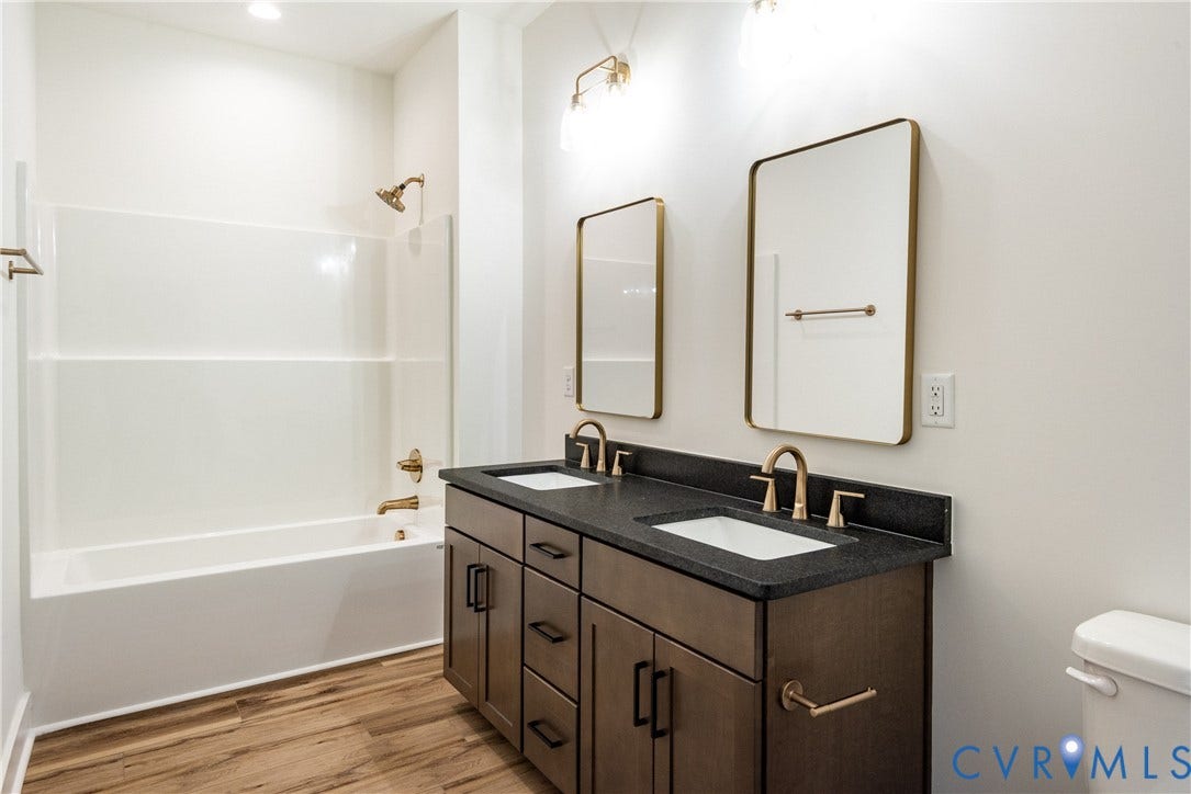 Dual-sink vanity with a dark countertop and gold-tone fixtures