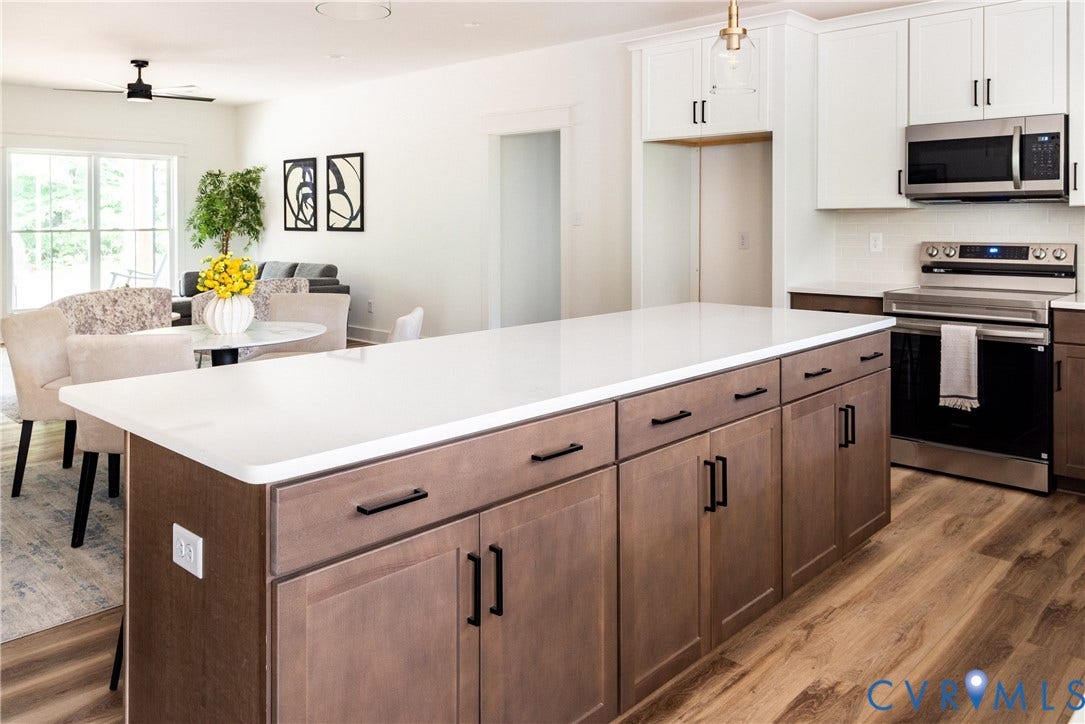 Kitchen island featuring white countertops, wood-finish cabinetry, and matte black hardware