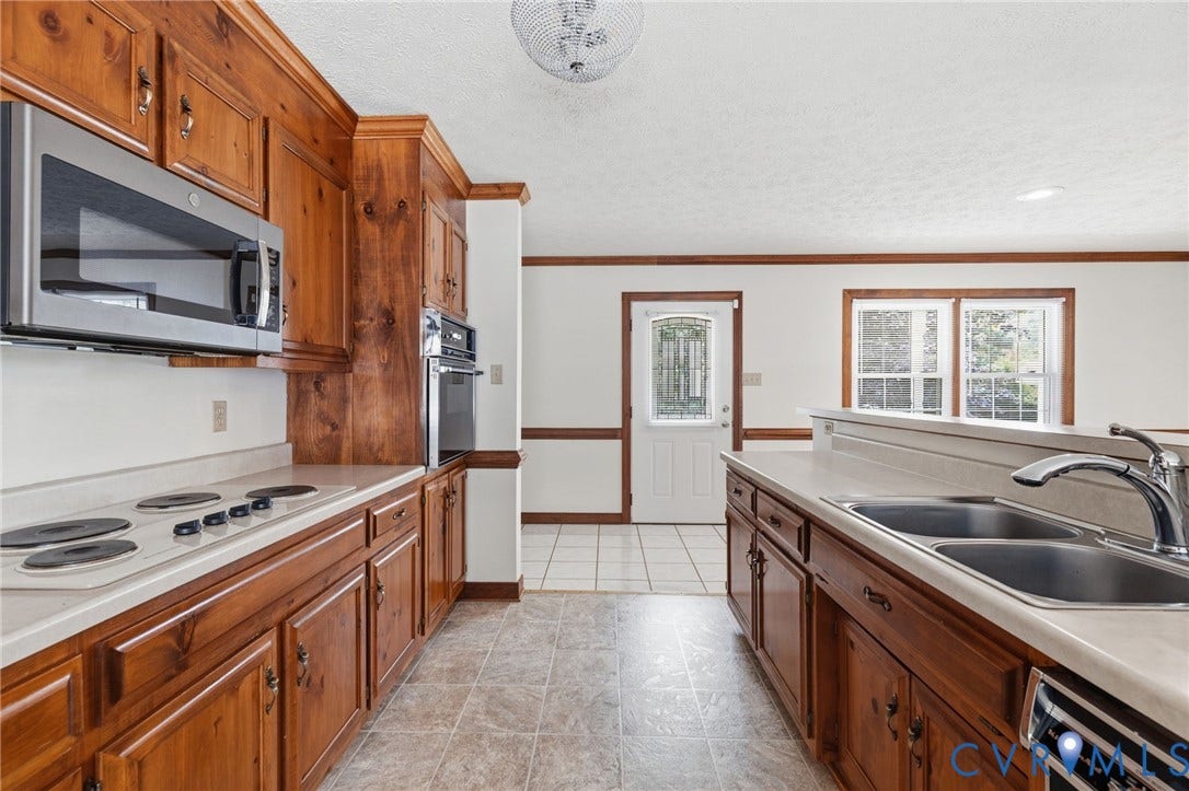Kitchen featuring wood cabinetry, stainless steel appliances, white countertops, and tile flooring