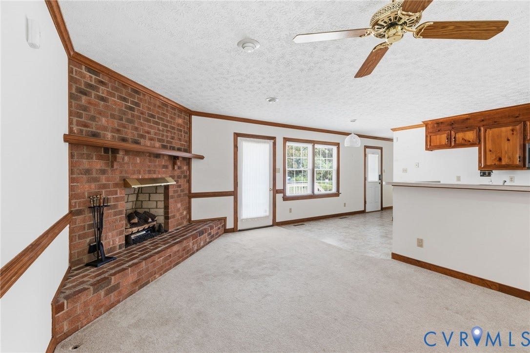 Brick fireplace with a substantial hearth, integrated wood mantel, and brass firebox surround