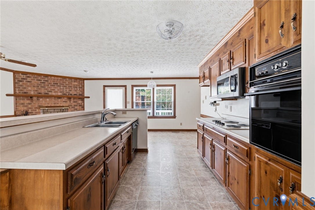 Kitchen featuring wood cabinetry, integrated wall oven, microwave, and a double basin sink