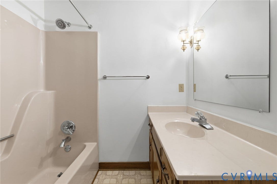 Bathroom featuring a tub/shower combination, a vanity with an integrated sink, a wall-mounted mirror, and overhead lighting