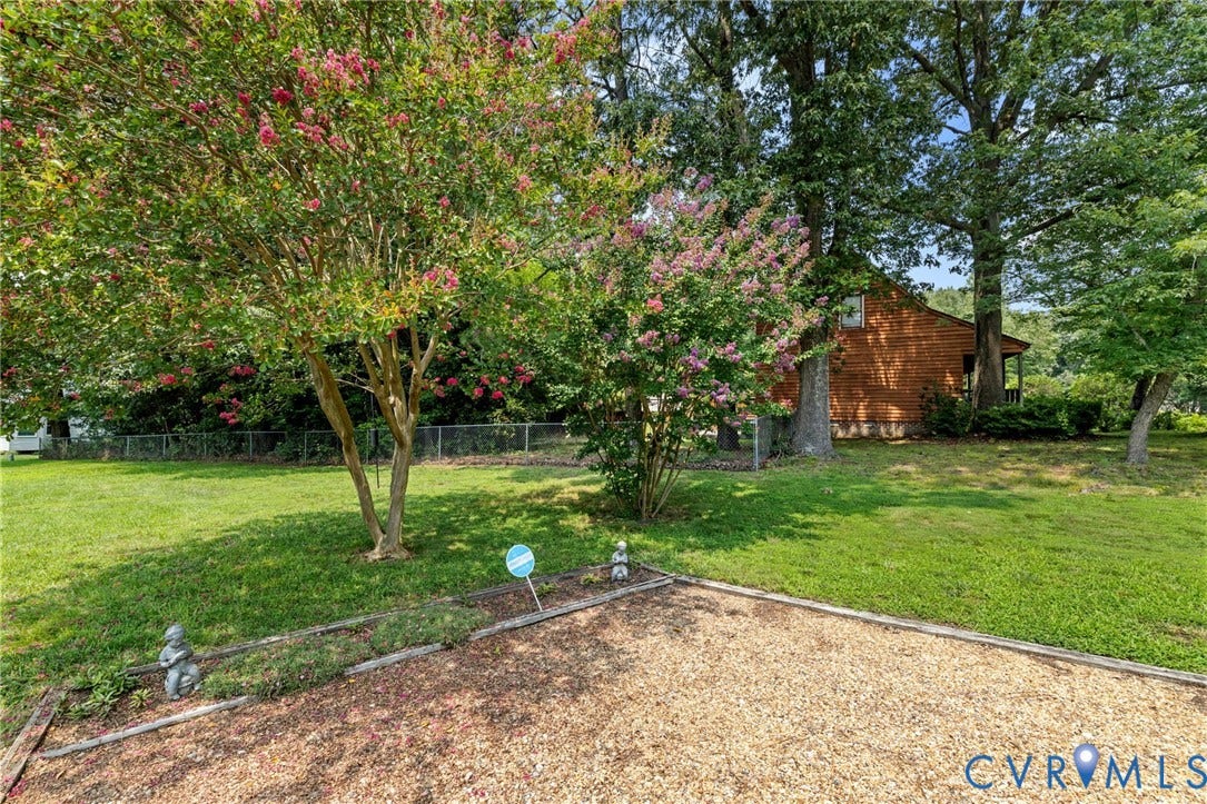 Spacious backyard featuring a lush lawn, mature trees, flowering shrubs, and a wood-sided structure