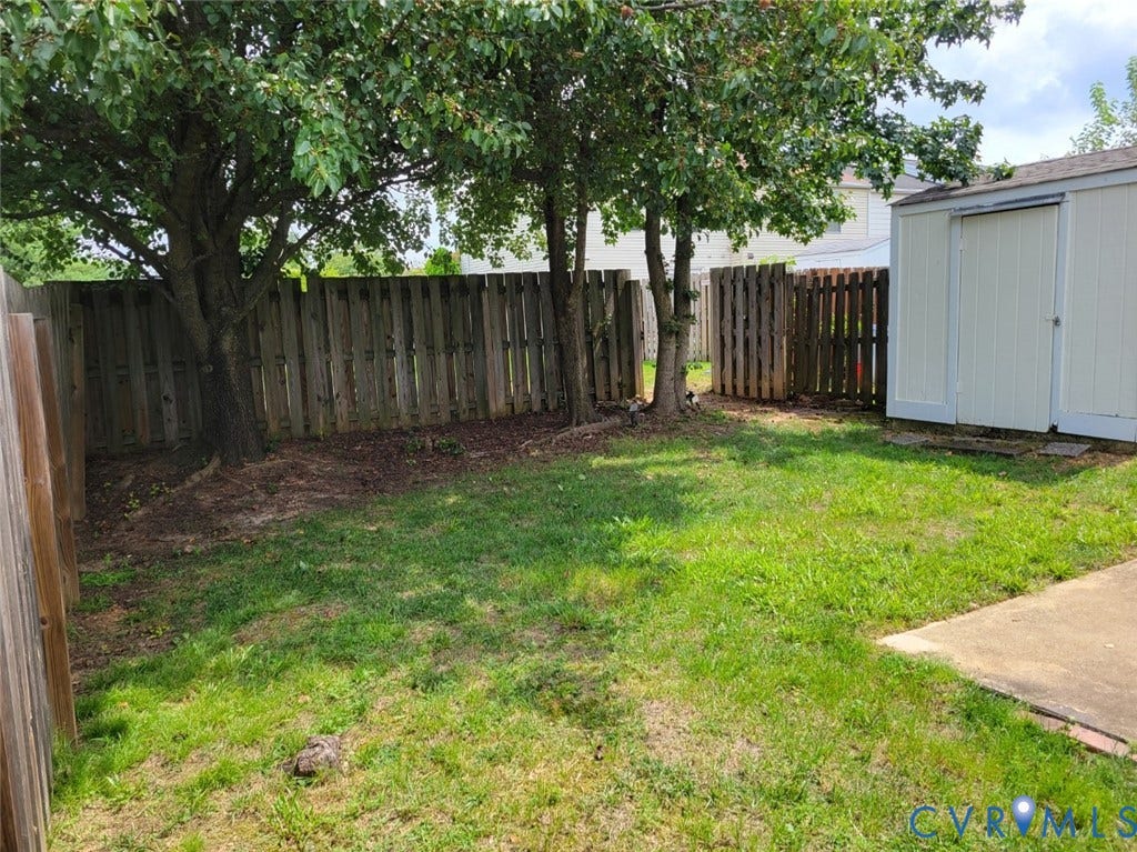 4900 Finnegan Court, Henrico, VA 23228 Fenced backyard featuring a mature tree, a privacy fence, a storage shed, and a concrete patio