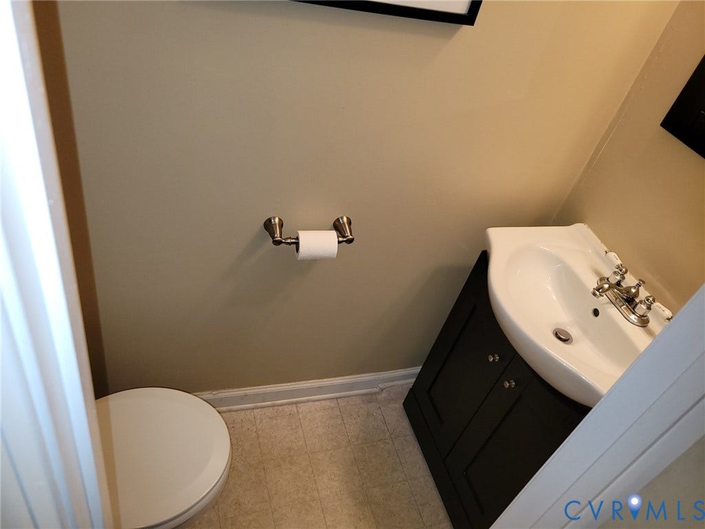 4900 Finnegan Court, Henrico, VA 23228 White ceramic toilet, corner vanity with dark cabinetry, integrated sink, and brushed nickel hardware