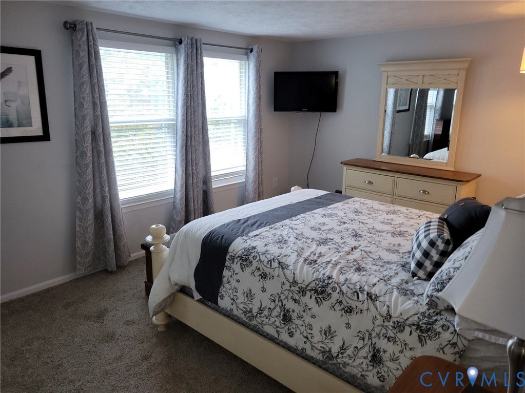 4900 Finnegan Court, Henrico, VA 23228 Two windows with blinds and curtains, wall-mounted television, built-in dresser with mirror, and carpeted flooring