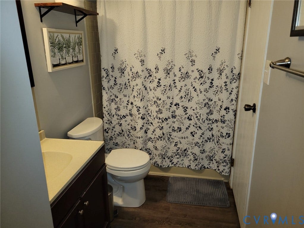 4900 Finnegan Court, Henrico, VA 23228 Bathroom featuring a vanity with an integrated sink, dark wood-finish cabinetry, neutral countertop, and LVP flooring