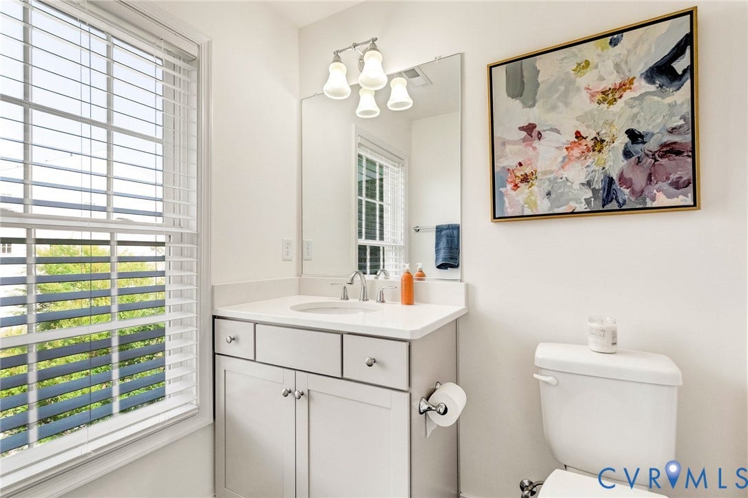 14379 Michaux Village Drive, Winterfield Park, Midlothian, VA 23113 Bright bathroom featuring a large window with white blinds, a vanity with a white countertop and base cabinetry, a wall-mounted mirror, and a toilet
