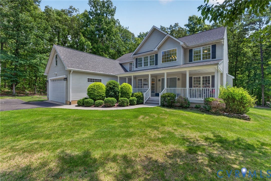 381 Shorewood Drive, Shorewood, Mineral, VA 23117 Two-story siding exterior with dark shutters, covered front porch, attached garage, and mature landscaping