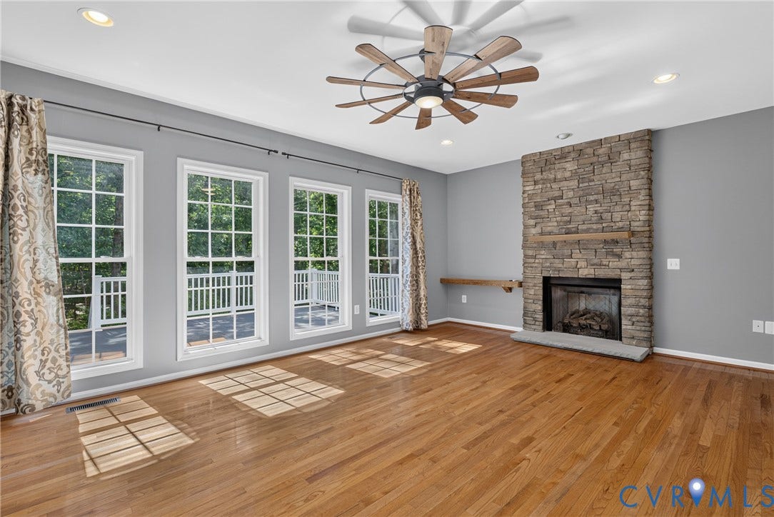 381 Shorewood Drive, Shorewood, Mineral, VA 23117 Spacious room featuring wood-finish flooring, a stone fireplace with a wood mantle, and a contemporary ceiling fan