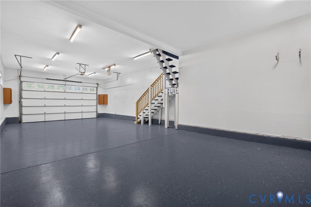 381 Shorewood Drive, Shorewood, Mineral, VA 23117 Two-car garage featuring a sectional garage door, speckled epoxy flooring, and a built-in staircase