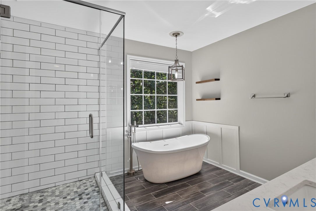 381 Shorewood Drive, Shorewood, Mineral, VA 23117 Bathroom featuring a freestanding soaking tub, clear glass shower enclosure with subway tile surround, wood-finish tile flooring, a window with grid pattern, and wainscoting